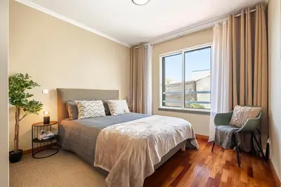 a bedroom with a bed and a chair and a window at SUPER Atalaia in Caniço