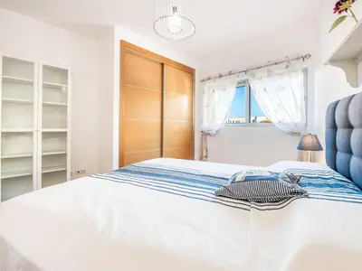 a white bedroom with a bed and a blue chair at Apt. A Nice Home in Lagos