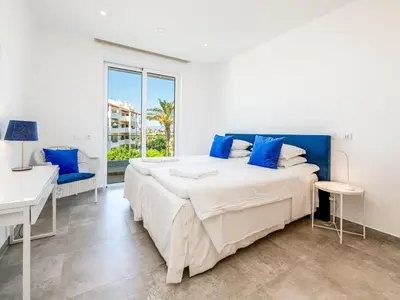 a white bedroom with a large bed and a desk at Apt. Seabreeze in Lagos