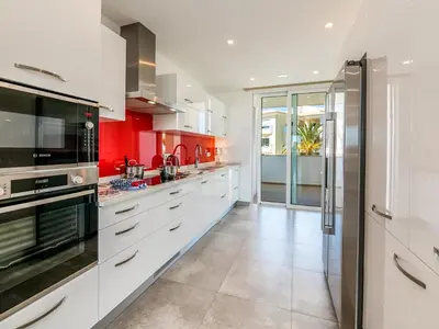 a kitchen with white cabinets and red walls at Apt. Seabreeze in Lagos