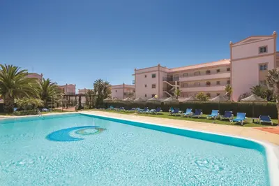 a swimming pool in a resort with chairs and a building at Apt. Palmeira in Luz