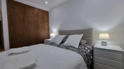 a bedroom with a large bed and a wooden wall at Lexus Apartment - Garajau in Caniço