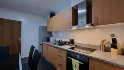 a kitchen with wooden cabinets and a counter top at Lexus Apartment - Garajau in Caniço