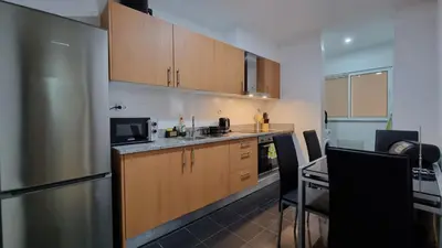 a small kitchen with wooden cabinets and a refrigerator at Lexus Apartment - Garajau in Caniço