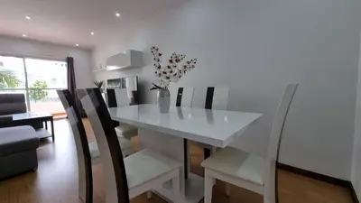 a white dining room table with chairs and a vase with flowers at Lexus Apartment - Garajau in Caniço