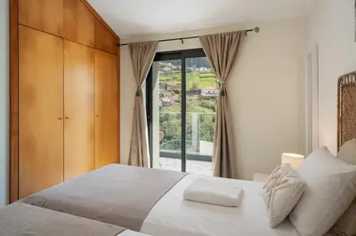 a bedroom with a bed and a large window at Villa Island Roots by An Island Apart in Calheta