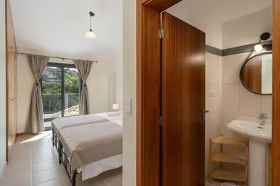 a bedroom with a bed and a bathroom with a sink at Villa Island Roots by An Island Apart in Calheta