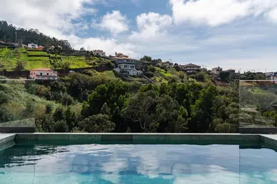 a swimming pool in front of a hill with houses at Villa Island Roots by An Island Apart in Calheta