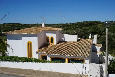 a white house with yellow windows and a roof at Casa 3 in Raposeira