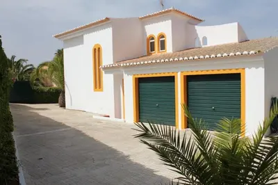 a white house with two green garage doors at Casa 3 in Raposeira