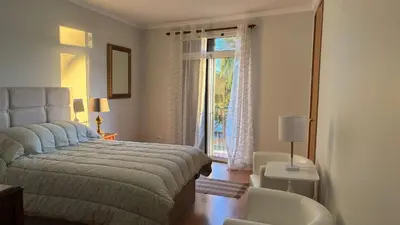 a bedroom with a bed and a chair and a window at Vista Praia Apartment in Funchal