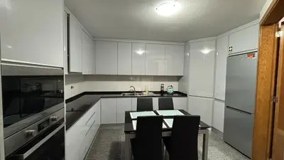 a kitchen with white cabinets and a table and a sink at Vista Praia Apartment in Funchal