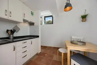 a kitchen with white cabinets and a wooden table at Apartment Amado - Carrapateira in Carrapateira