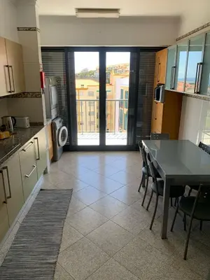 a kitchen with a table and chairs and a balcony at Barreiros View Vacations in Funchal