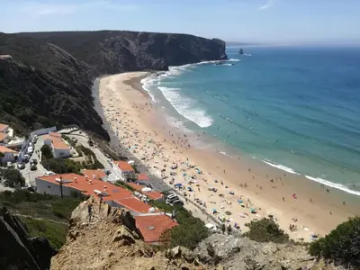 a beach with a bunch of people and the ocean at Casa Francis in Aljezur