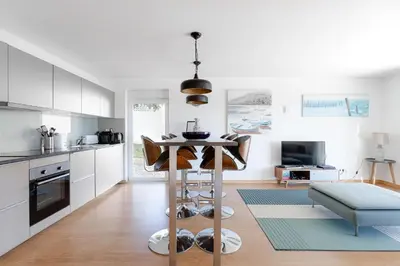 a kitchen with white cabinets and a table with chairs at Luz Home- Two Bedroom Villa in Luz