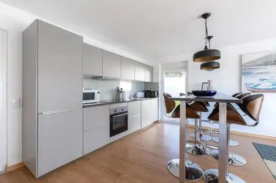 a kitchen with white cabinets and a table at Luz Home- Two Bedroom Villa in Luz