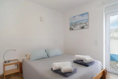 a white bedroom with a bed with towels on it at Luz Home- Two Bedroom Villa in Luz