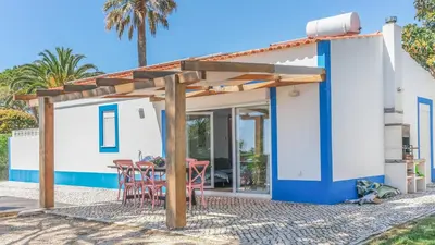 a cottage with a table and chairs under a pergola at Luz Home- Two Bedroom Villa in Luz