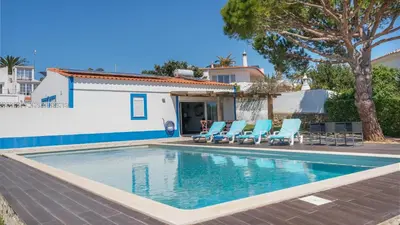 a swimming pool with chairs and a house at Luz Home- Two Bedroom Villa in Luz