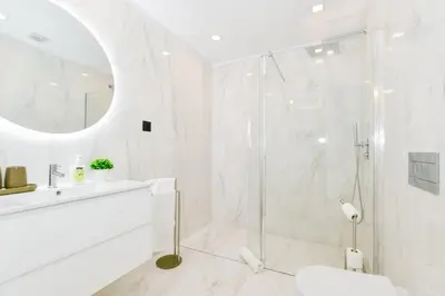 a white bathroom with a shower and a sink at Cantinho do Atlântico in Funchal