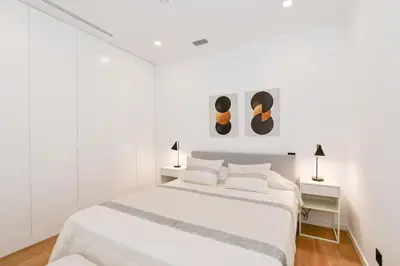 a white bedroom with a white bed and two lamps at Cantinho do Atlântico in Funchal