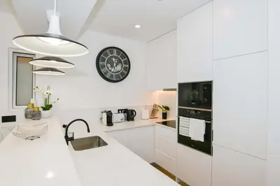 a kitchen with white cabinets and a clock on the wall at Cantinho do Atlântico in Funchal