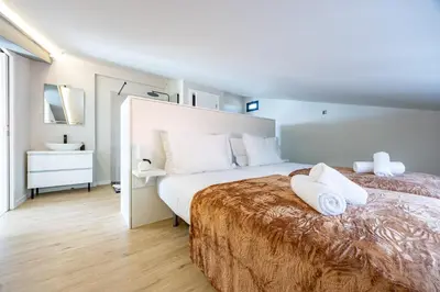 a white bedroom with a large bed with white pillows at Palm Breeze Loft in Estreito da Calheta