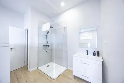 a white bathroom with a shower and a sink at Palm Breeze Loft in Estreito da Calheta