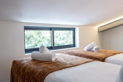 two beds in a room with two windows at Palm Breeze Loft in Estreito da Calheta