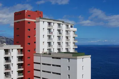 a red and white building next to the ocean at Apartamento do Mar in Funchal