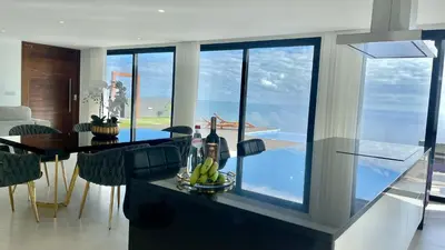 a kitchen and dining room with a view of the ocean at Villa Nóbrega in Câmara de Lobos