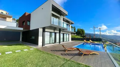 a house with a swimming pool and two chairs at Villa Nóbrega in Câmara de Lobos