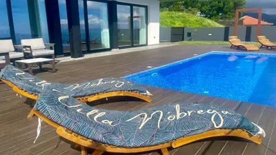 a swimming pool with a bench next to a house at Villa Nóbrega in Câmara de Lobos