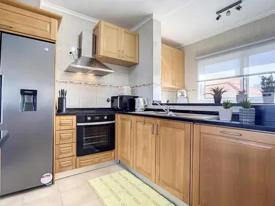 a kitchen with wooden cabinets and a stainless steel refrigerator at Zen House By The Madeira Luxury Collection in Arco da Calheta