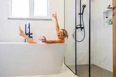a woman is sitting in a bath tub with a glass at Zen House By The Madeira Luxury Collection in Arco da Calheta