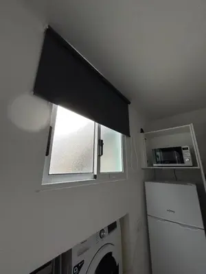 a window with a black blind in a laundry room at Celina Residence in Ribeira Brava