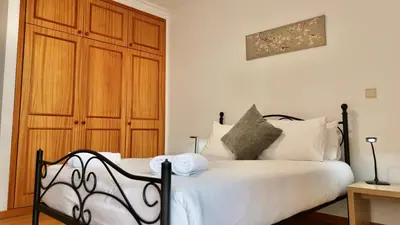 a bedroom with a white bed with a wooden closet at Green Haven in Funchal