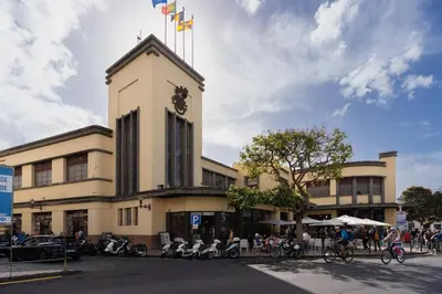 a building with a clock tower with people riding bikes at Oudinot Residence by Mercado dos Lavradores com AC in Funchal