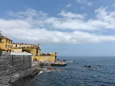 a group of people on a beach near the water at Oudinot Residence by Mercado dos Lavradores com AC in Funchal