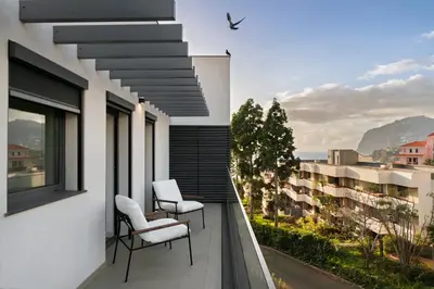 a balcony with two chairs and a view of a building at Acqua Residence II by An Island Apart in Funchal