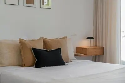 a bedroom with a white bed with pillows and a table at Acqua Residence II by An Island Apart in Funchal