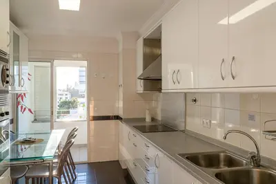 a kitchen with white cabinets and a sink and a table at GuestReady - Charming retreat in Funchal in Funchal