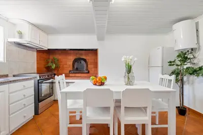 a white kitchen with a white table and chairs at SUPER Sunset in Ponta Delgada