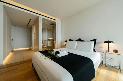 a bedroom with a large white bed with a black blanket at Savoy Residence Monumentalis VA by LM&AC Signature in Funchal