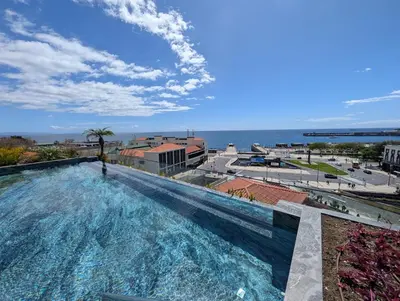a swimming pool with the ocean in the background at Savoy Residence City Loft - Style and Sophistication in Funchal