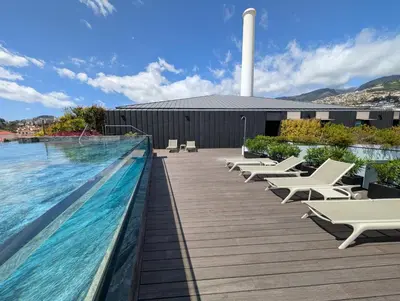 a swimming pool with chaise lounge chairs next to a building at Savoy Residence City Loft - Style and Sophistication in Funchal