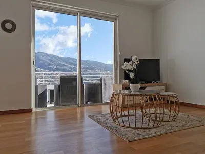 a living room with a table and a large window at Pico Barcelos - Funchal in Funchal