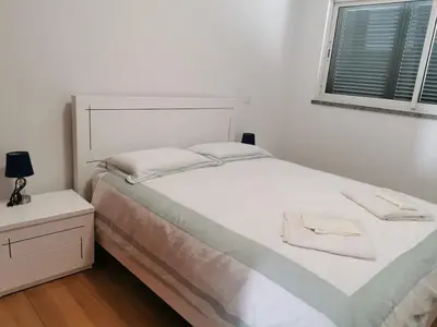 a white bedroom with a bed and a window at Pico Barcelos - Funchal in Funchal