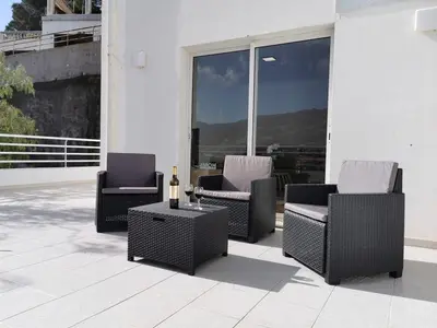 a patio with three chairs and a table with a bottle of wine at Pico Barcelos - Funchal in Funchal